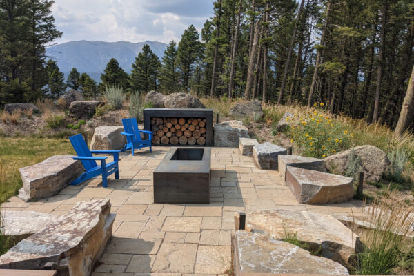 Modern Patio with Montana flagstone and boulders and custom steel fire pit and wood rack looking at Bridger mountains